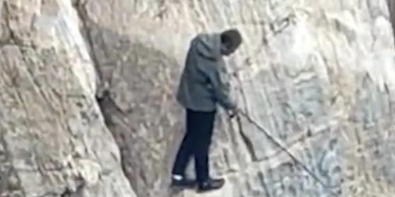 有惊无险！男子站临海近乎垂直的石壁上钓鱼